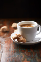 Amaretti (Italian biscuits) and a cup of coffee on rustic wooden background. Close up.