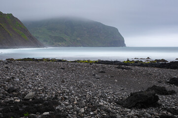 Atlantic ocean coastline on Azores, Faj&atilde; Grande, Flores island, Portugal. Stones, rocks and water in long exposure. Nature photography in motion. Black lava shore.