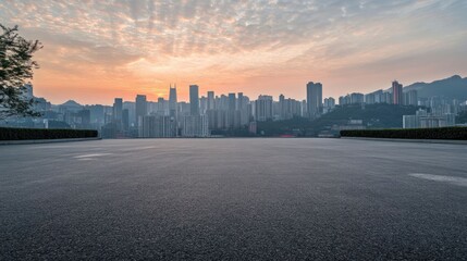 An empty asphalt road with a city skyline and sunrise in the background.