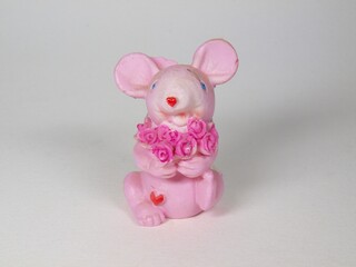 Figurine. Toy. A pink mouse holds a bouquet of flowers in its paws. Product photography.