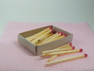 A box of matches that lies on a pink napkin.