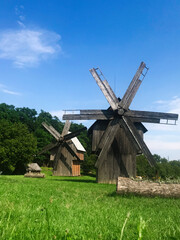 Fototapeta premium Wooden windmills in a lush green countryside landscape