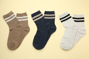 Different comfortable socks on beige background, flat lay