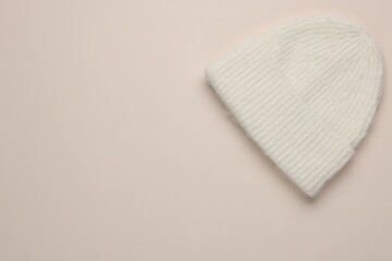 Warm woolen hat on beige background, top view. Space for text