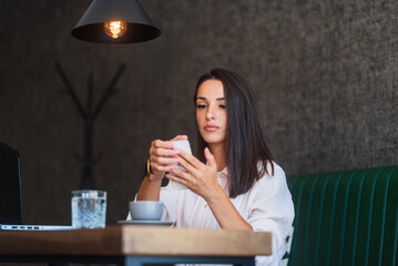 Businesswoman reading text message on smartphone in cafe