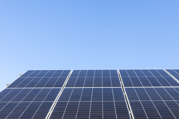 Aerial view of solar panel cells on clear blue sky background. Alternative energy concept. Modern house with solar panels stand-alone photovoltaic plant system on household metal sheet roof