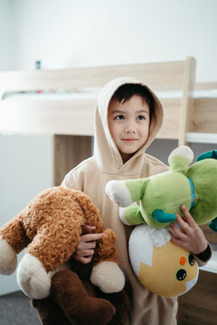 Young boy holding plush toys inside his bedroom