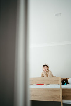 Young boy sitting on top of the bunk bed.