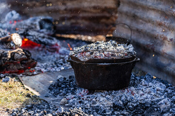camp oven cooking damper bread on fire coals shielded by corrugated iron