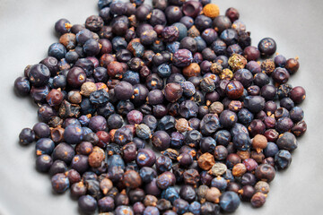 Dried Juniper berries in gray plate as a organic natural superfood used in traditional and contemporary health-focused diets. Top view