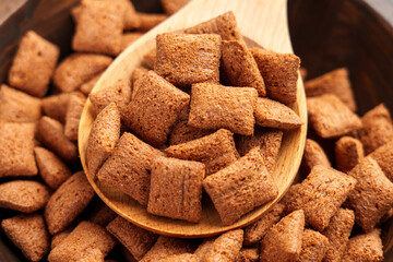 Brown corn cereal pillows with a rich chocolate crust in wooden spoon, capturing their crispy...