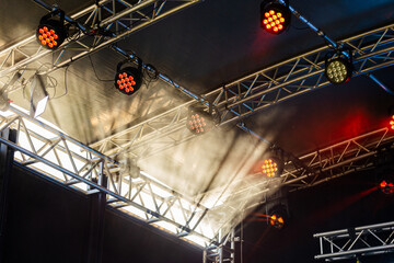 Sun rays through mist with lights above stage at outdoor concert event