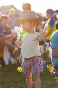 Hazy sunlight over toddler girl playing with ball on elastic string at event