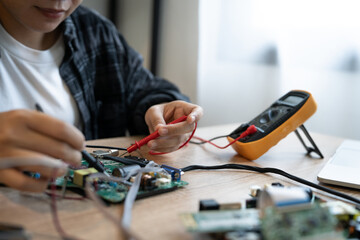 A person is working on a circuit board with a multimeter. The person is focused and determined to...