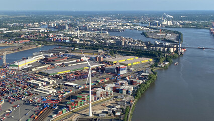 Fototapeta premium Aerial View of Industrial Port with Shipping Containers and Wind Turbine