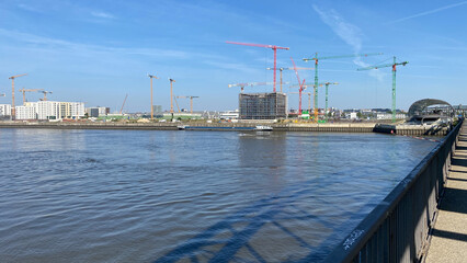 Urban Riverfront Construction Site with Cranes Under Clear Sky