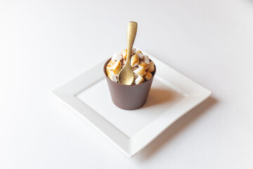 A glass made from chocolate milk with a chocolate spoon and marsmellows on white plate isolated on white background, concept for menus or recipe 