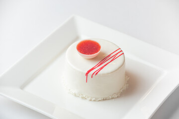 Colorful layered mousse cakes topped with fresh berries, decorative chocolate, standing on white plate isolated on  white background.