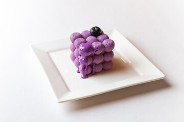 French mousse cake covered with violet glaze, shape of cube