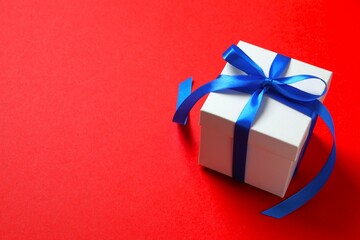 Beautiful gift bos tied with golden bow on color background 