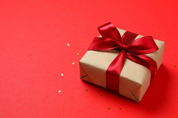 Beautiful gift bos tied with golden bow on color background 
