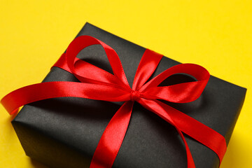 Beautiful gift box tied with golden bow on color background 