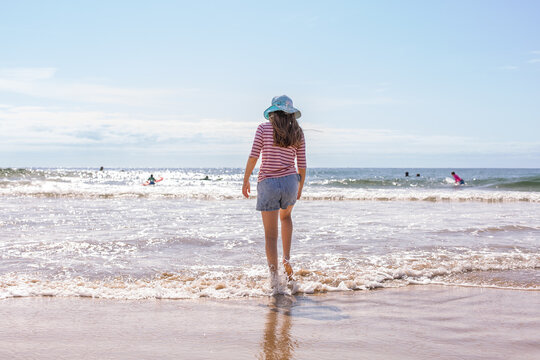 10 year old girl standing in the waves at the beach