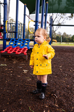 toddler in a yellow raincoat at a playground