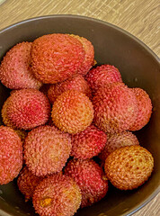  Fresh lychees in a bowl on a wooden table, close up