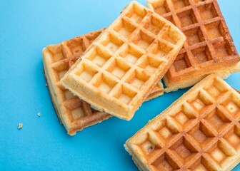 Delicious Waffles Isolated on a Vibrant Blue Background: A Top-View Delight Perfect for Food Lovers and Breakfast Enthusiasts, Showcasing Their Golden Crisp Texture and Warm Color