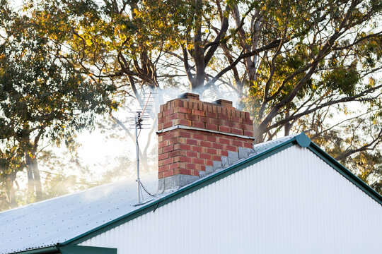 smoke from brick chimney of white cottage on winter evening