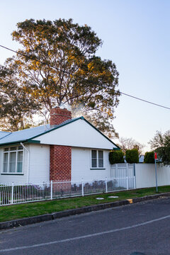 Fifty year old white cottage on the corner of roads in suburban area of country town