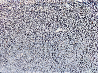 Textured asphalt surface with small stones under bright sunlight
