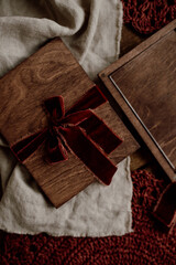 Mockup of a glass gift certificate in a wooden box on a wooden background decorated with burgundy velor ribbons. Close-up