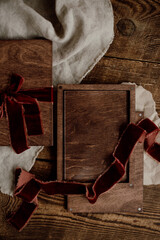 Mockup of a glass gift certificate in a wooden box on a wooden background decorated with burgundy velor ribbons.