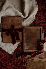 Mockup of a glass gift certificate in a wooden box on a wooden background decorated with burgundy velor ribbons. A baking option for a postcard