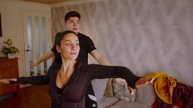 Attractive young couple doing yoga exercises at home