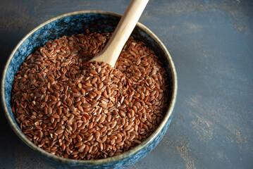Flax seeds in a blue bowl with a wooden spoon, highlighting natural nutrition.