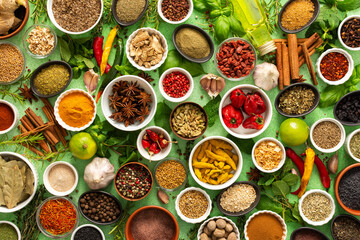 A vibrant assortment of fresh, multicolored spices and herbs on a delicate green background,...