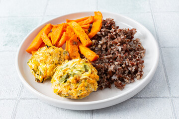 A delicious and wholesome plate featuring brown rice, sweet potatoes, and chickpea pancakes made...