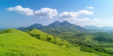 Vast green hills under a clear blue sky with distant mountains in the background.