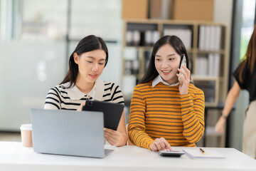 Two Asian female students wearing headphones chatting in an online chat meeting using a laptop. Female college students learn remotely