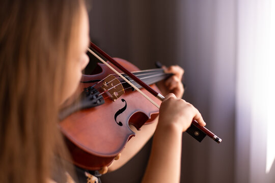child playing notes on a violin deep in concentration