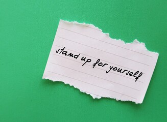 Torn note on green copy space background written Stand up for yourself - assertiveness concept - ability to express your opinions and needs in a calm and open way - having boundaries and be assertive