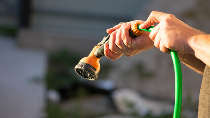 lawn watering hose in hand. sprinkler, irrigation water, watered the backyard. green hose, orange...