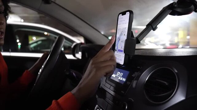 Delivery driver checking her phone for gps navigation while driving through the city at night