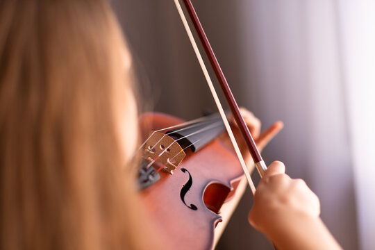 focus on violin bow, bridge and strings while a child plays