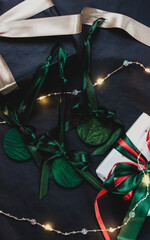 Green Christmas tree ornaments with satin bows surrounded by gifts and garland, festive holiday decorations in vibrant green hue