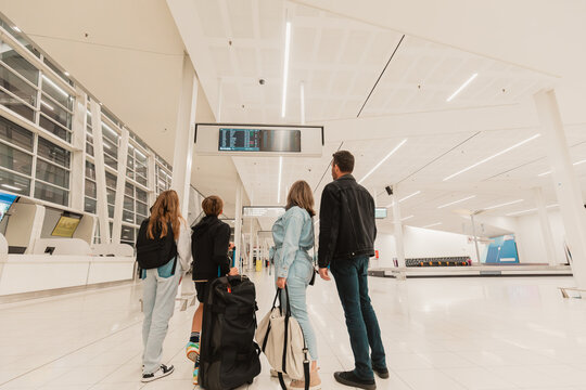 Family of four checking flight times on board at airport