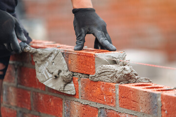 Skilled mason laying bricks with precision and attention to detail during construction in bright daylight